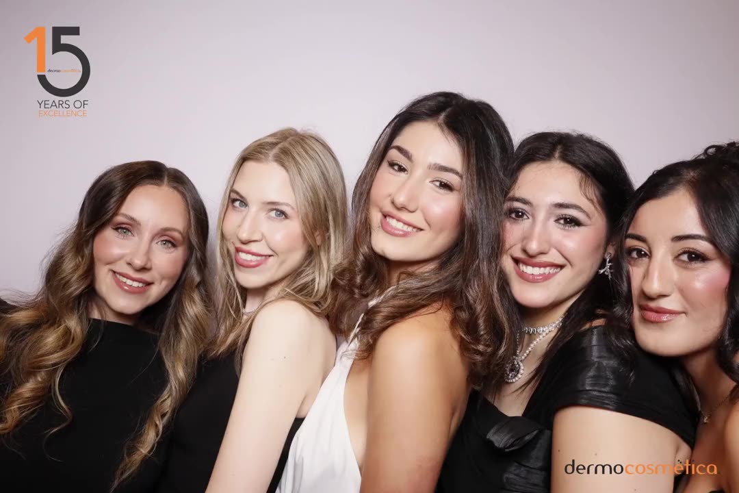 Five guests posing close together in front of a white photo booth backdrop