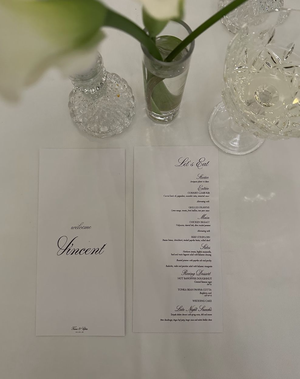 Wedding reception place setting with a printed menu and a guest name card on a white tablecloth