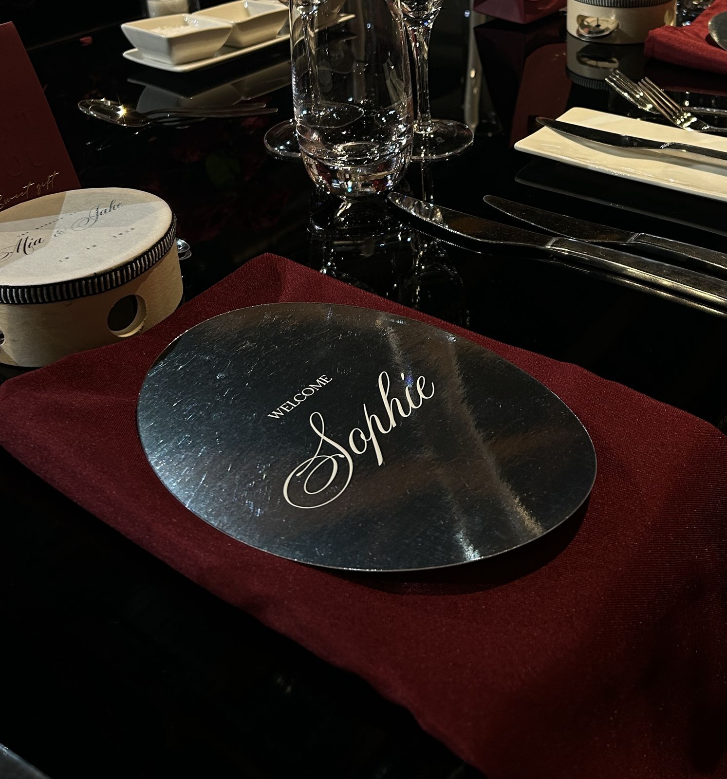 Mirror place card with a guest name on a dark wedding reception table setting