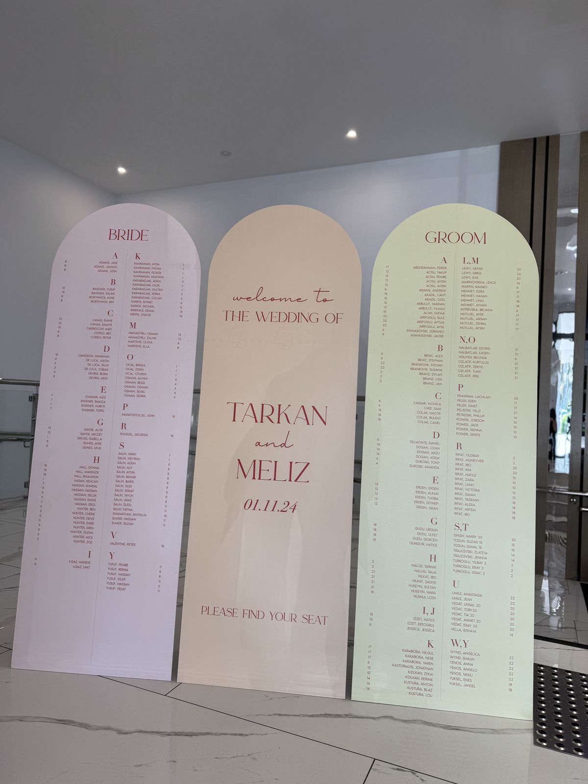 Three pastel arches: a pink arch headed Bride, a peach welcome arch for Tarkan and Meliz reading Please find your seat, and a green arch headed Groom